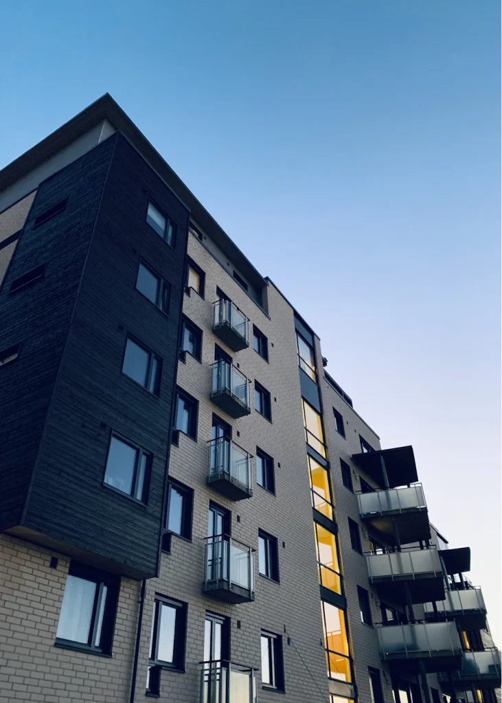 Modernt flerbostadshus med vita balkonger mot en ljusblå himmel