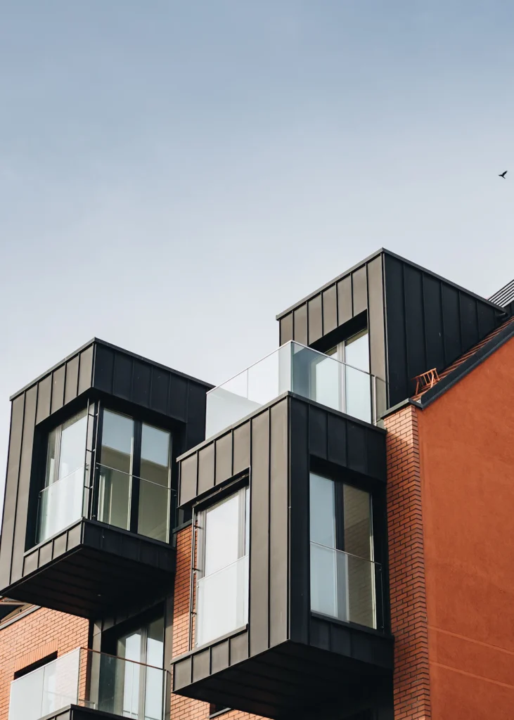 Mörk plåtklädd takpåbyggnad på ett flerbostadshus i tegel