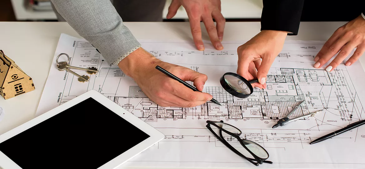 Arkitekter granskar en planritning med förstoringsglas